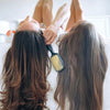 Two models posing while holding the UNbrush Detangling Hair Brush in Sunburst Yellow