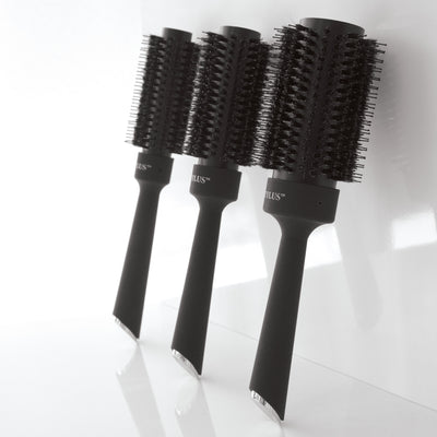 3 Different sizes of the Boar Bristle Blowout Brushes leaning against a wall.