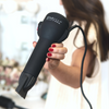 Model holding the hair dryer with attached concentrator nozzle in front of camera.